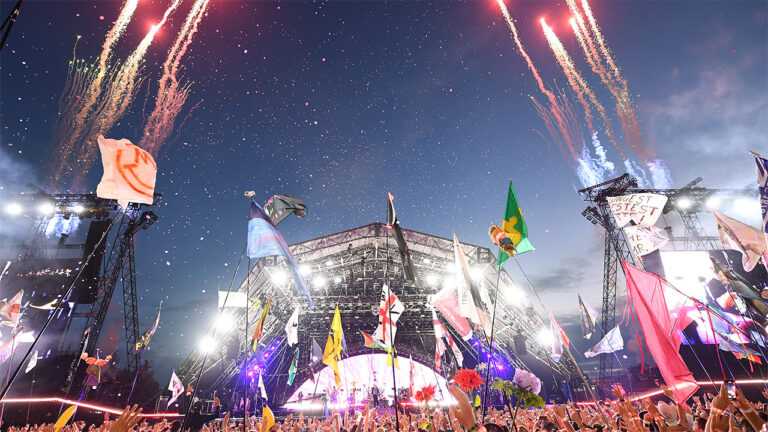 Night time view of Glastonbury Festival stage with crowd and fireworks