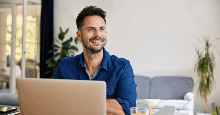 A man sits at a table with an open laptop.