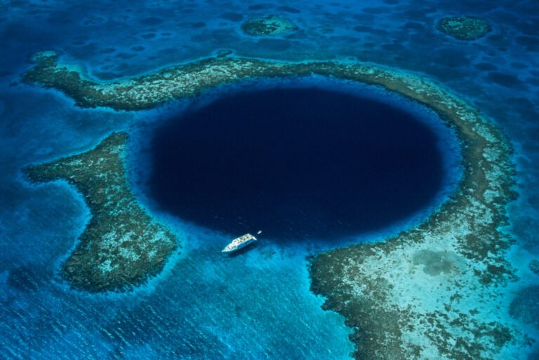 Belize, Lighthouse Reef, boat moored at Blue Hole, aerial view.