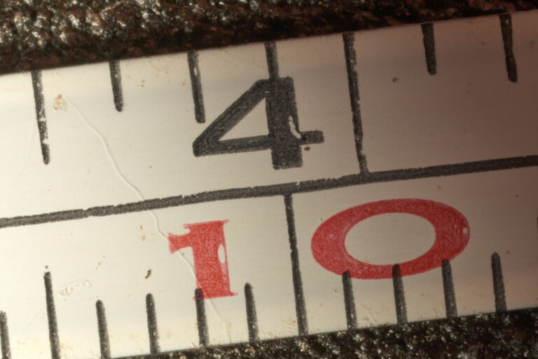 Close-up view of a measuring tape highlighting the four-inch mark with a precise measurement of one-tenth of an inch, emphasizing accuracy and precision in measuring length.