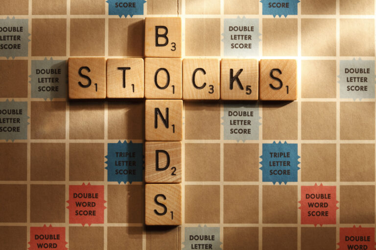 The words &quot;stocks&quot; and &quot;bonds&quot; spelled out on a Scrabble board and connected by the letter &quot;o&quot;