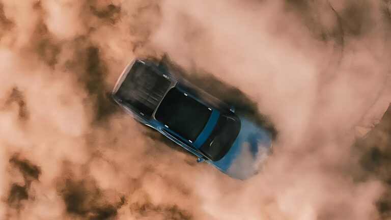 An image of a Rivian R1T Quad from above shown spinning in a massive dusty deserty