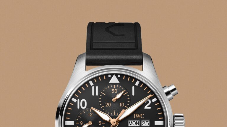 A close-up view of the top half of the IWC Pilot’s Watch Chronograph 41 APXGP against a light tan backgroun