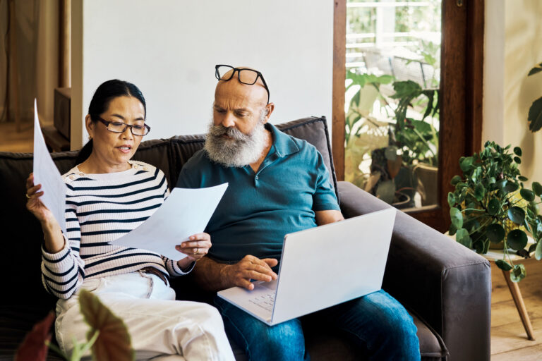 This is the Best CD to Get Amid Rate Uncertainty A couple discussing their finances sitting on a couch with a laptop