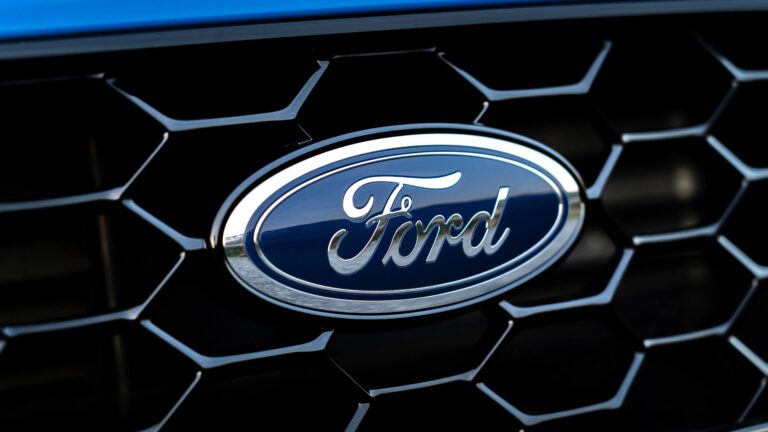 Close-up of a blue and silver Ford logo on a black honeycomb grille.