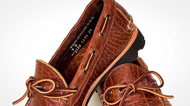 Pair of brown leather boat shoes with moc toe stitching, leather laces threaded through metal eyelets, and black rubber soles. The leather has a textured, slightly distressed finish.