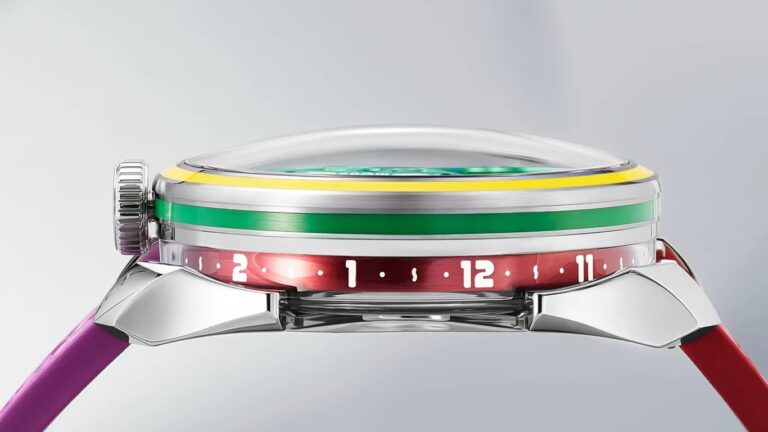 Side view of a M.A.D.Editions wristwatch with a domed crystal, a silver case, and a colorful bezel featuring yellow and green stripes. The watch has a red ring with white numerals and dots around the edge, and the strap is two-toned with purple on the left and red on the right. The crown is silver and textured for grip.