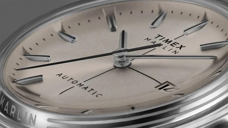 Close-up of a Timex Marlin automatic watch face with a steel dial, steel hour markers, and hands. The watch has a date window at the 3 o