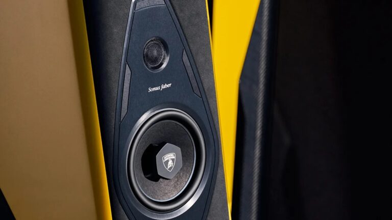 Close-up of a Sonus faber speaker integrated into a yellow and black surface, featuring a tweeter at the top and a larger woofer below with the Automobili Lamborghini logo on the woofer