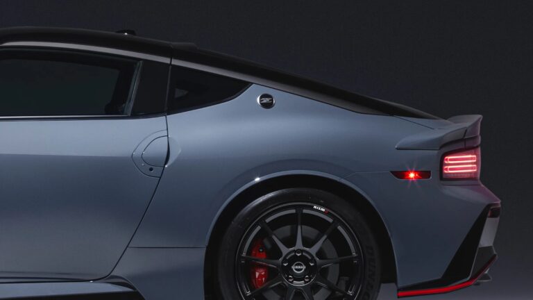 Rear side view of a sleek, modern sports car in matte gray with a black roof. The car features a distinctive