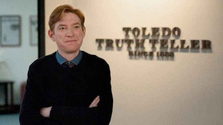 I’ve just streamed all 10 episodes of ‘The Office’ spinoff ‘The Paper’ — and it’s so much better than I thought it’d be Ned (Domhnall Gleeson) poses, arms crossed, in front of the Toledo Truth Teller sign in a scene from Peacock's "The Paper"
