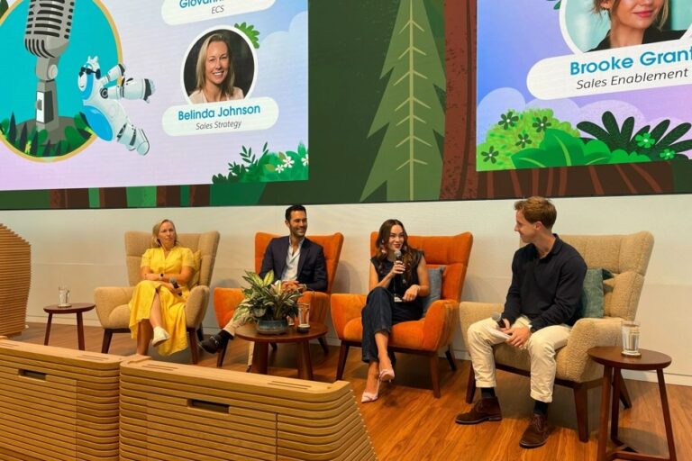 A panel of four professionals is engaged in a discussion on stage at a Salesforce event.