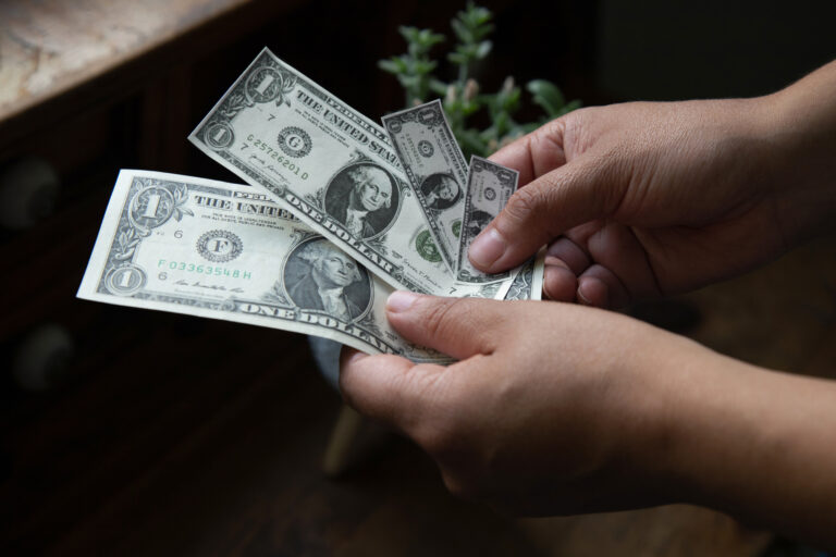 The Rule of the Shrinking Dollar in Retirement Hands holding shrinking dollar bills, inflation concept.