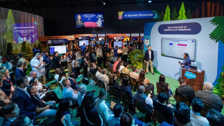 Your 5-Minute Guide to Dreamforce A group of attendees at Dreamforce 2024 sit in and watch two presenters deliver a Salesforce on Salesforce presentation