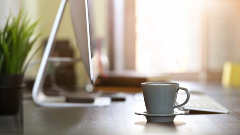 9 Morning Habits of Successful Business Owners Morning light on desk computer and coffee cup.